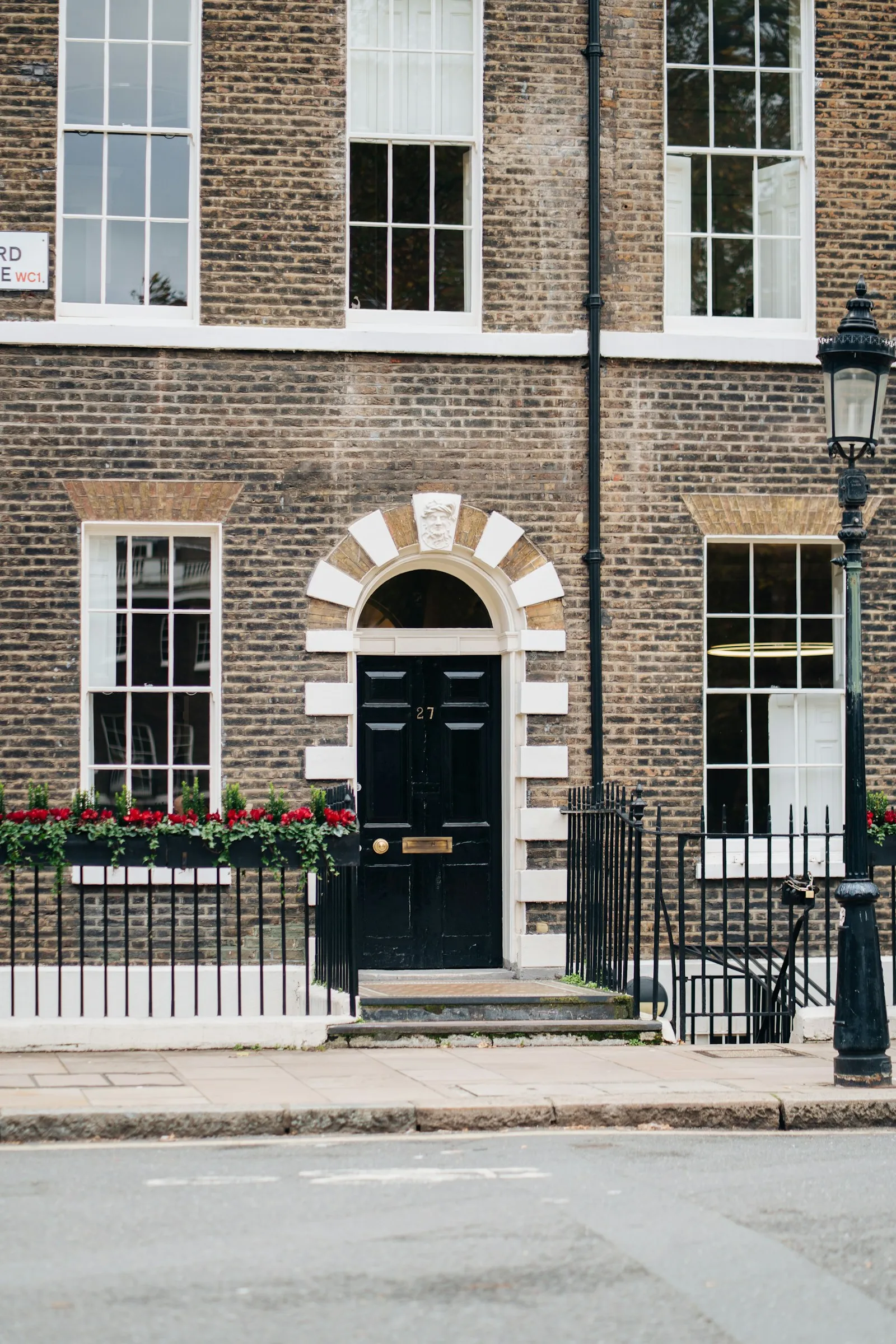 A traditional British brick townhouse with a glossy black painted front door